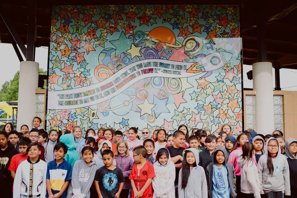 Students stand in front of a finished mural they helped design